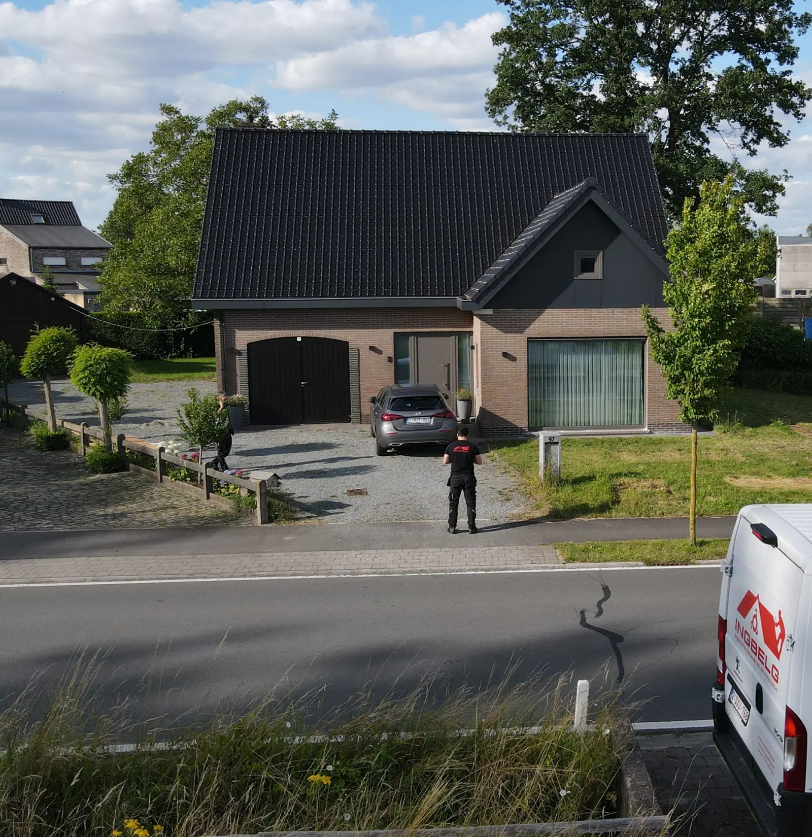 Woning met een nieuw donker pannendak, met een medewerker en de bestelwagen van INGBELG voor de deur