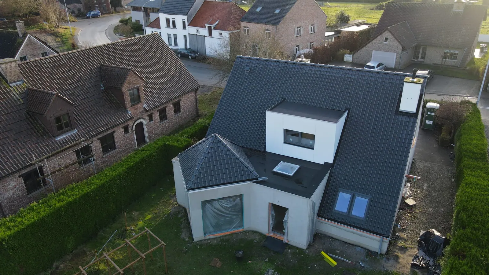 Woning met een nieuw antracietkleurig pannendak, een witte dakopbouw, dakvensters en een plat dak met lichtkoepel