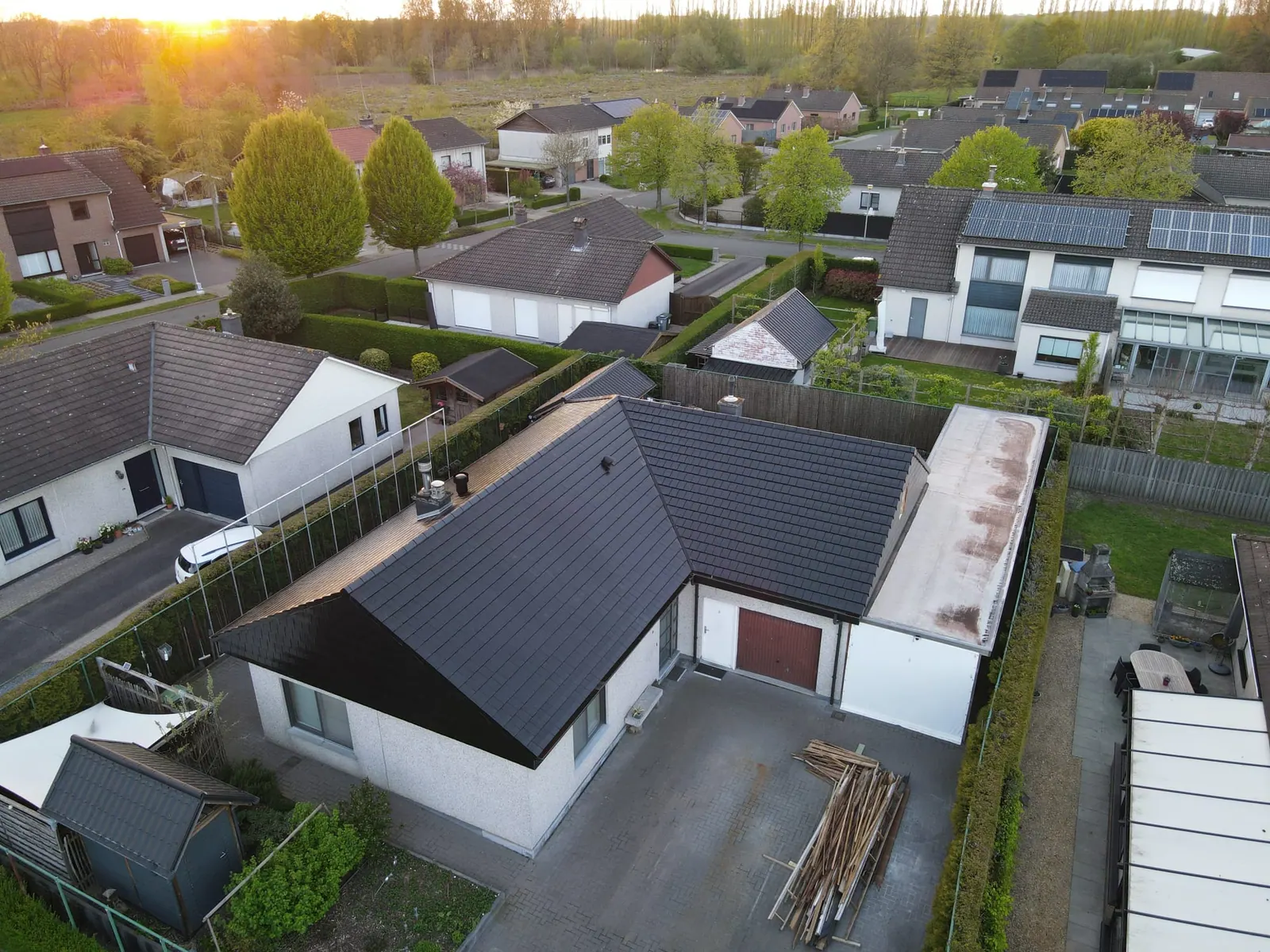 Luchtfoto van een bungalow met een nieuw donker dak en een plat dak ernaast